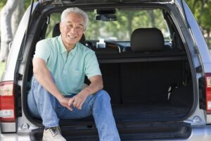 車のリアゲートに座っている男性